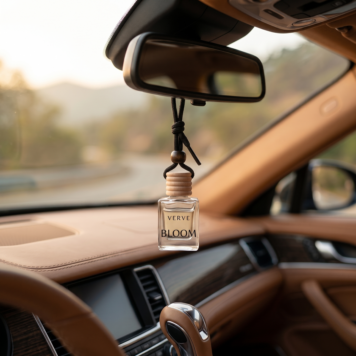 VERVE Bloom car perfume hanging from rear view mirror in warm tan leather interior